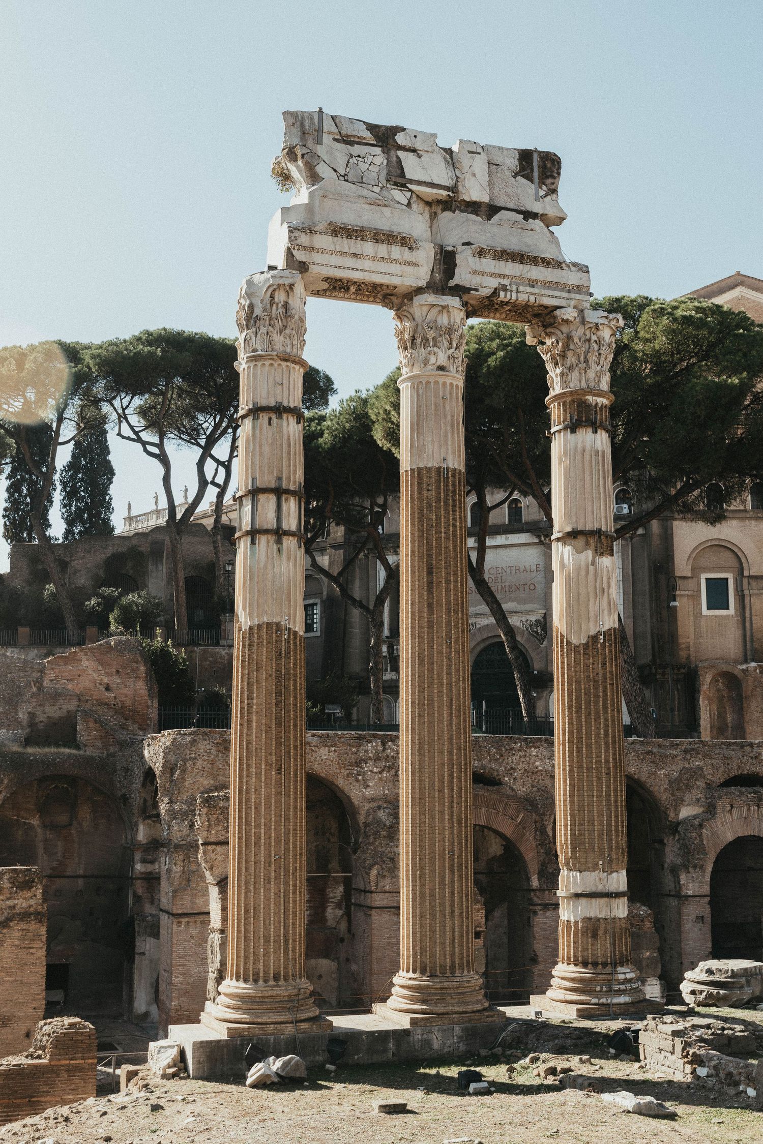 Ancient Roman Forum columns with Corinthian capitals standing against a clear blue sky.
