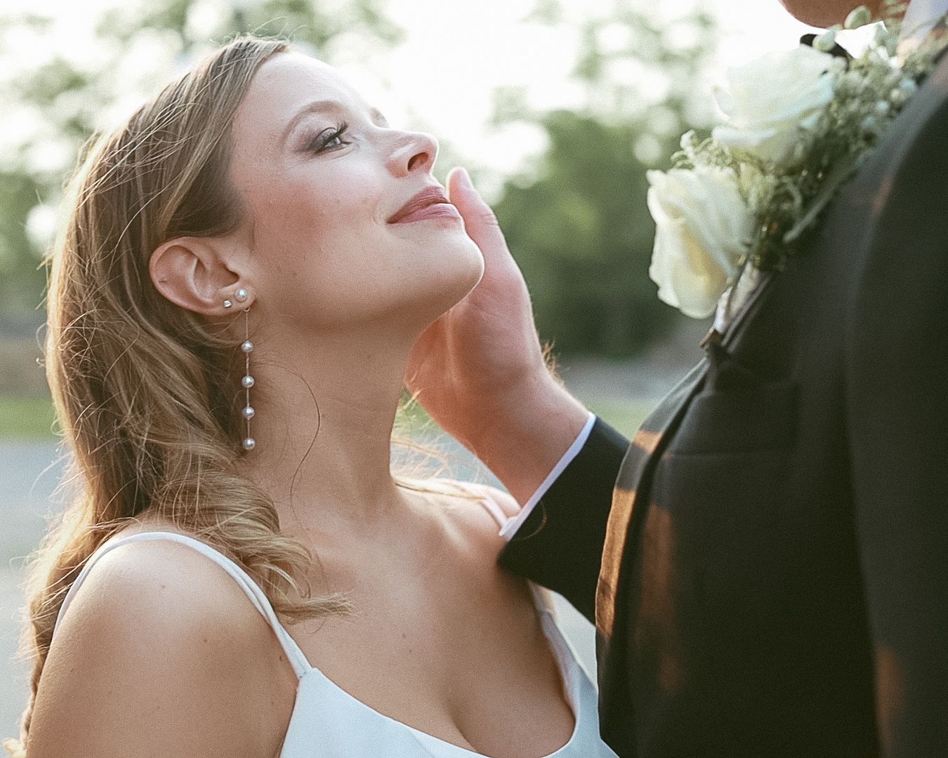 Close-up of a bride with pearl earrings looking up lovingly at a groom during golden hour in Stroudsburg, PA.
