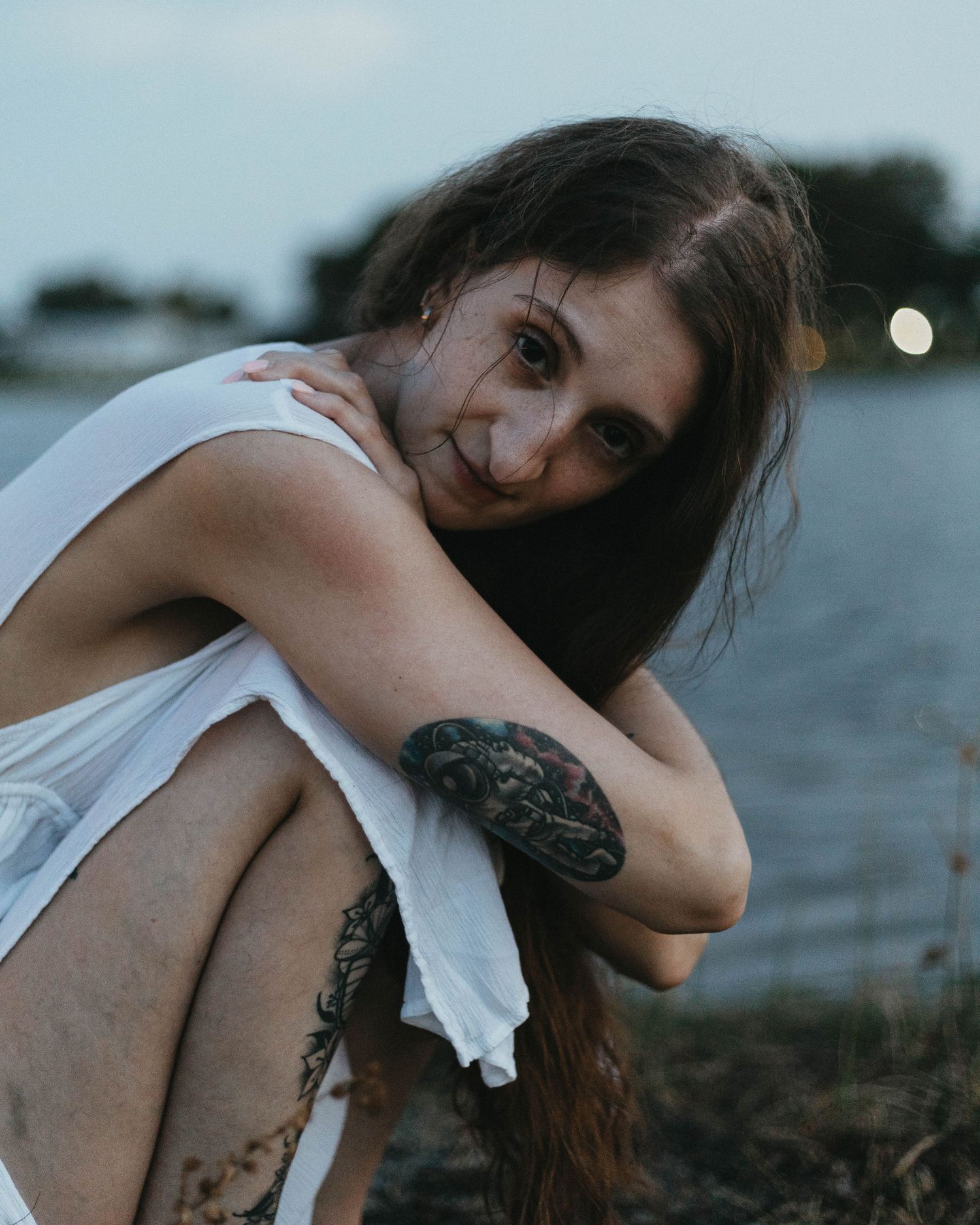 Artistic lifestyle portrait of a woman with an astronaut tattoo in a white dress, showcasing moody engagement photography in Scranton.