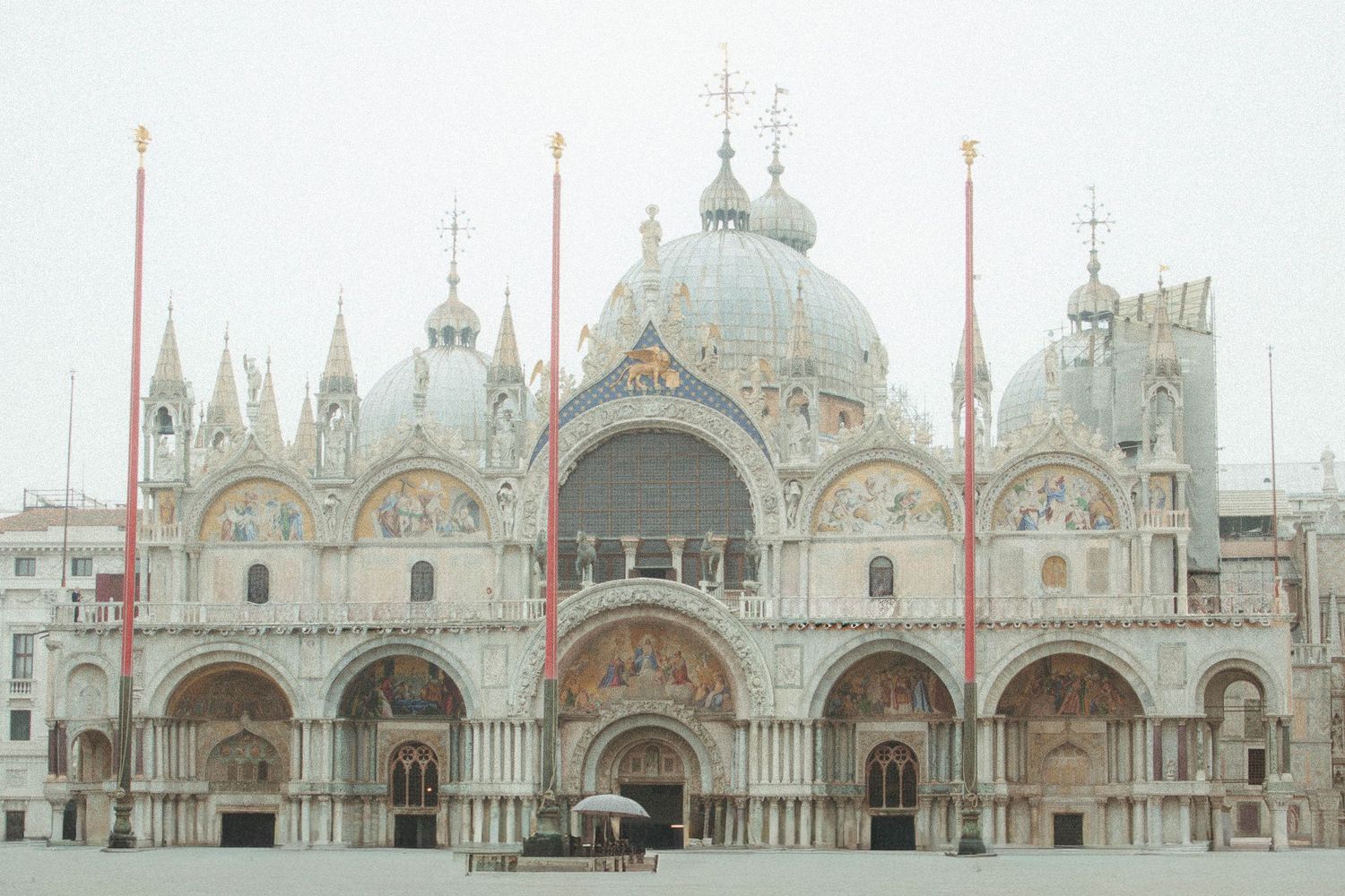 Ornate facade of St. Mark's Basilica on a foggy day in Venice's Piazza San Marco.