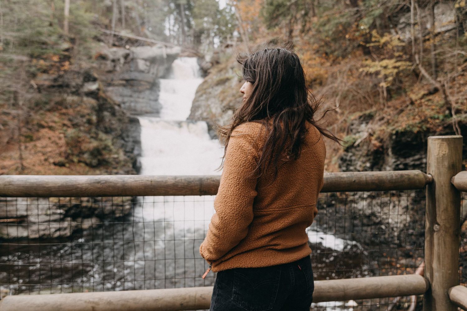 A woman looking out at a scenic waterfall in the Poconos, an ideal location for adventurous elopement photography in Northeast PA.