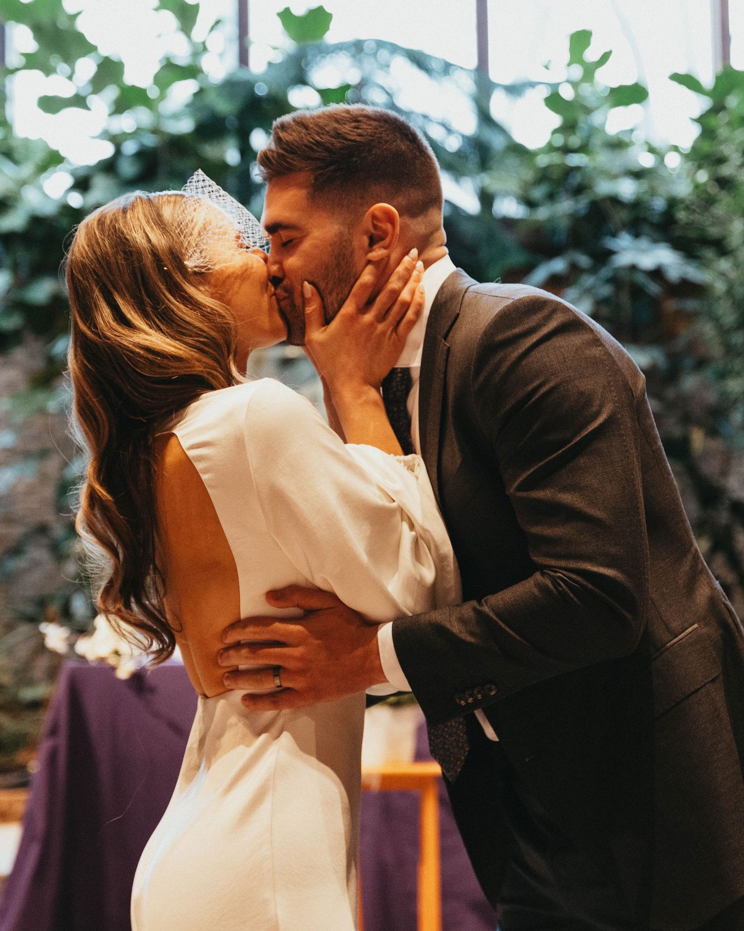 Bride and groom share their first kiss at the altar during their wedding ceremony indoors.