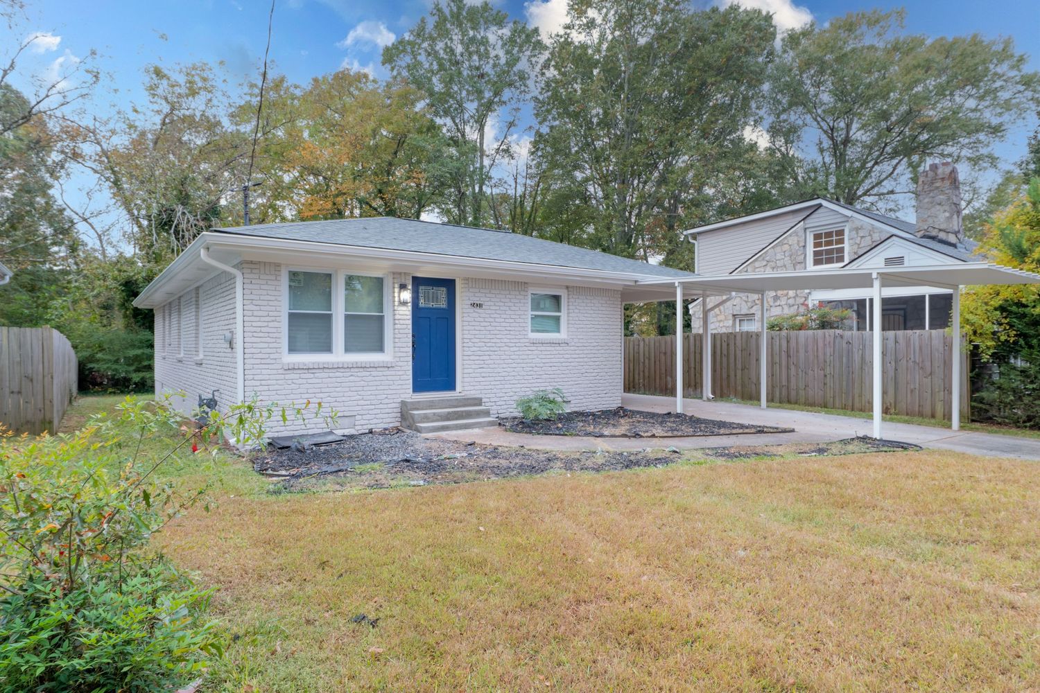Small pink ranch-style home with carport and front yard featuring white trim and concrete walkway.