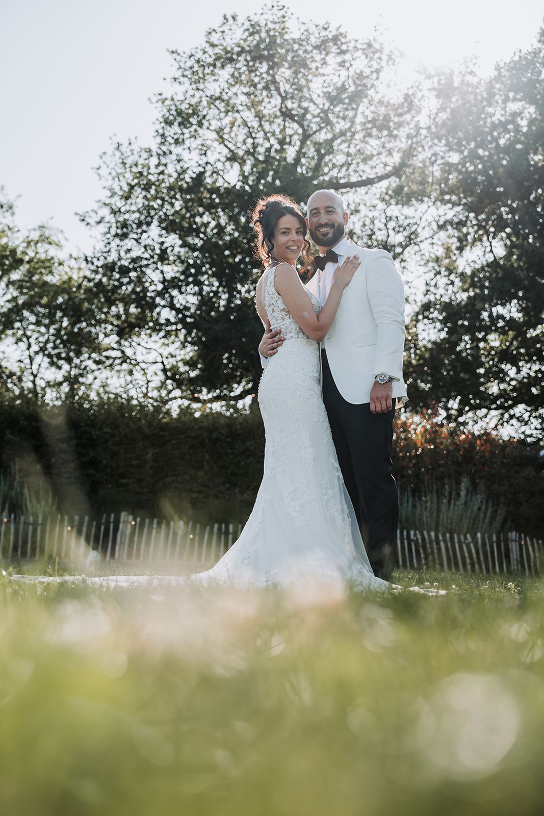 A couple shares a romantic moment in a sunlit meadow during their wedding photoshoot.