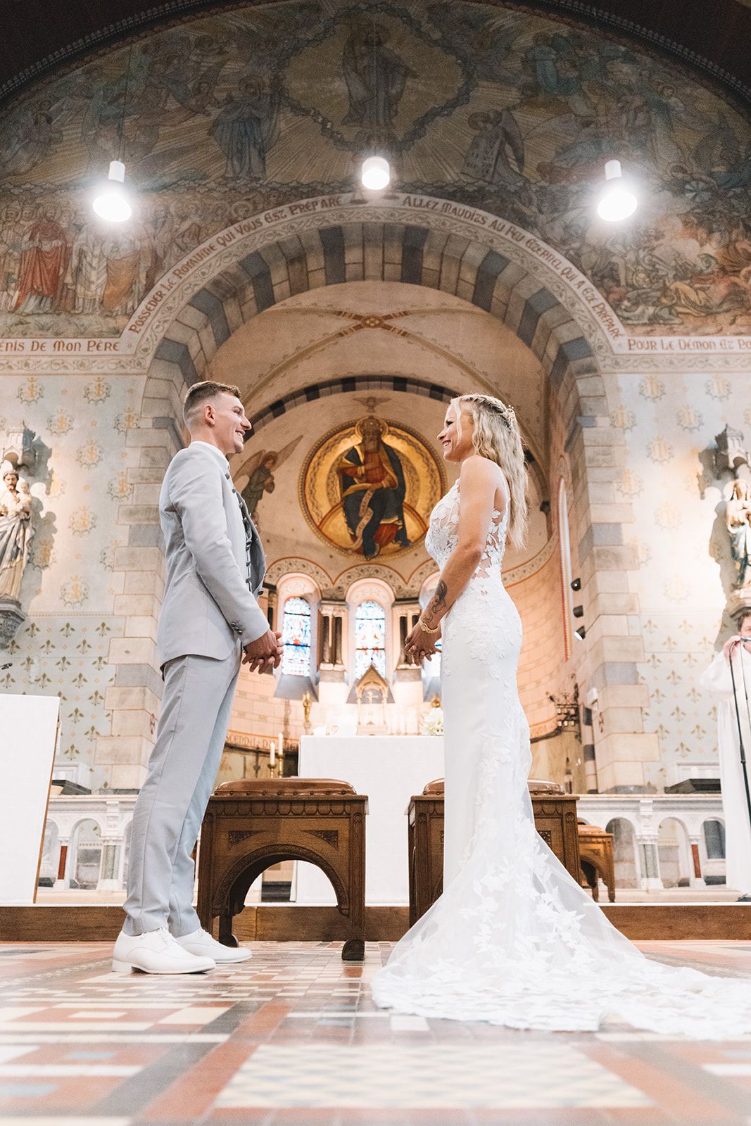 Wedding couple poses in a beautiful church with ornate arched ceilings and murals.