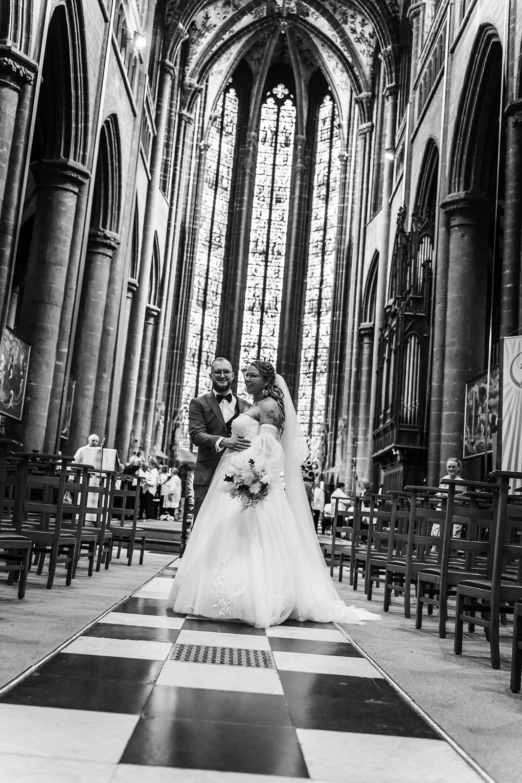 Elegant church interior with checkerboard floor and soaring Gothic arches captures wedding moments.