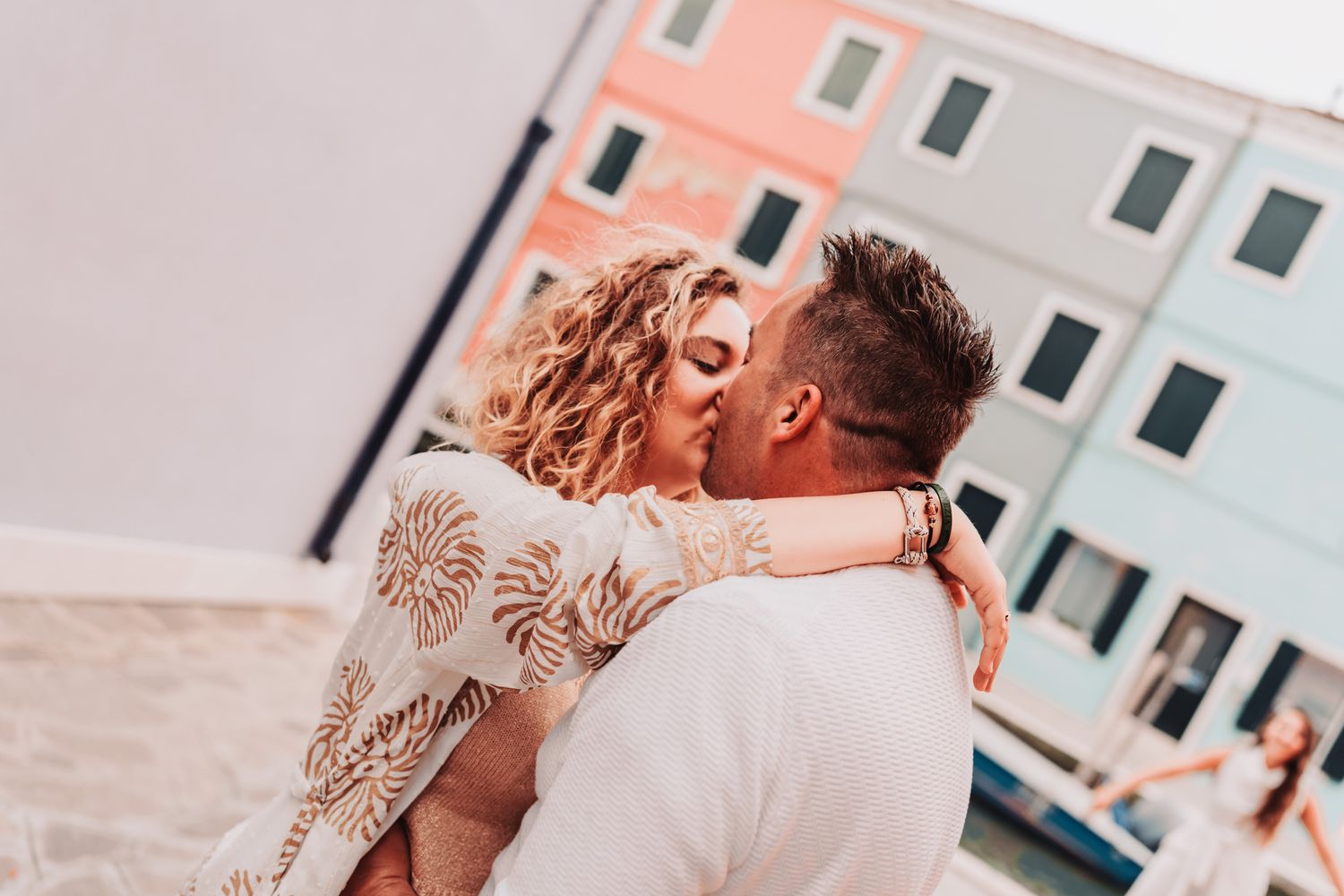 A tender embrace captured against pastel-colored buildings in Venice.