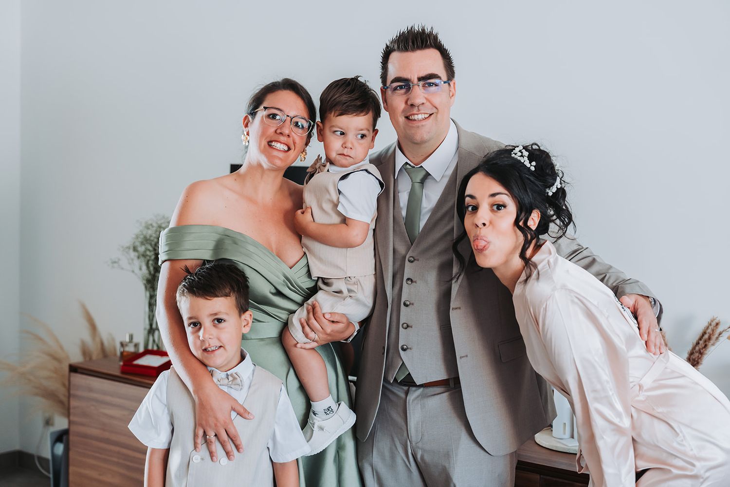 Fun family portrait with everyone making silly faces in formal attire.
