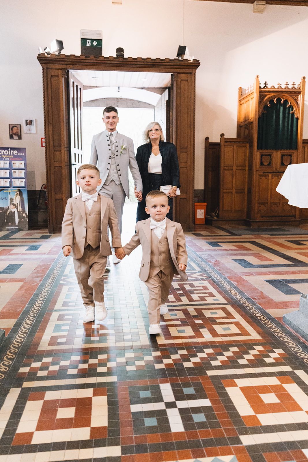 Children walk across a geometric patterned church floor during a wedding ceremony.