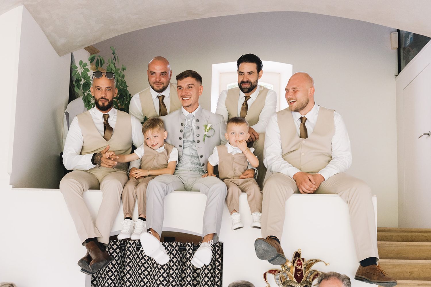 Wedding party members gathered on stairs sharing candid moments and laughter.