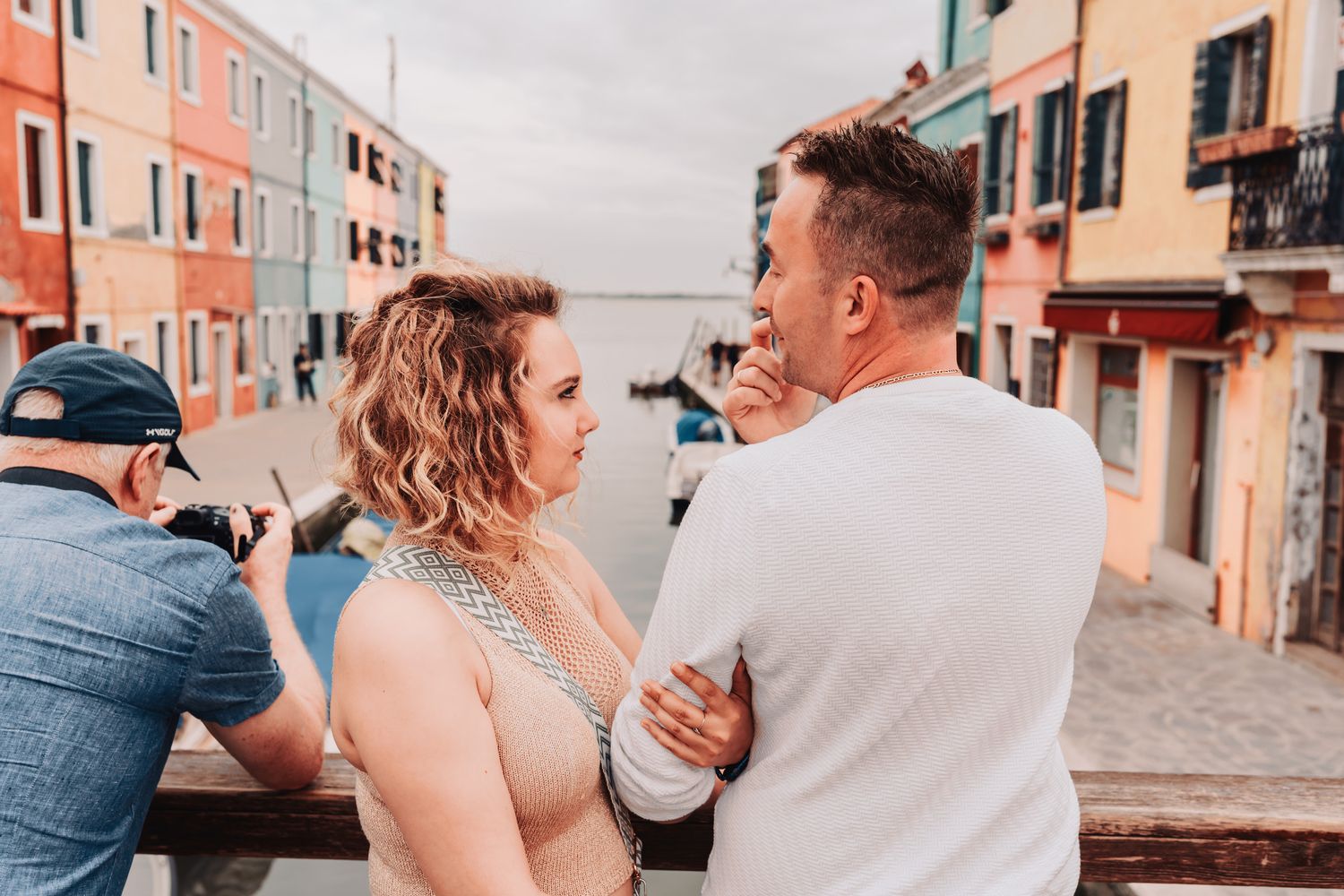 Couple sharing intimate moment on colorful street in casual wedding attire.