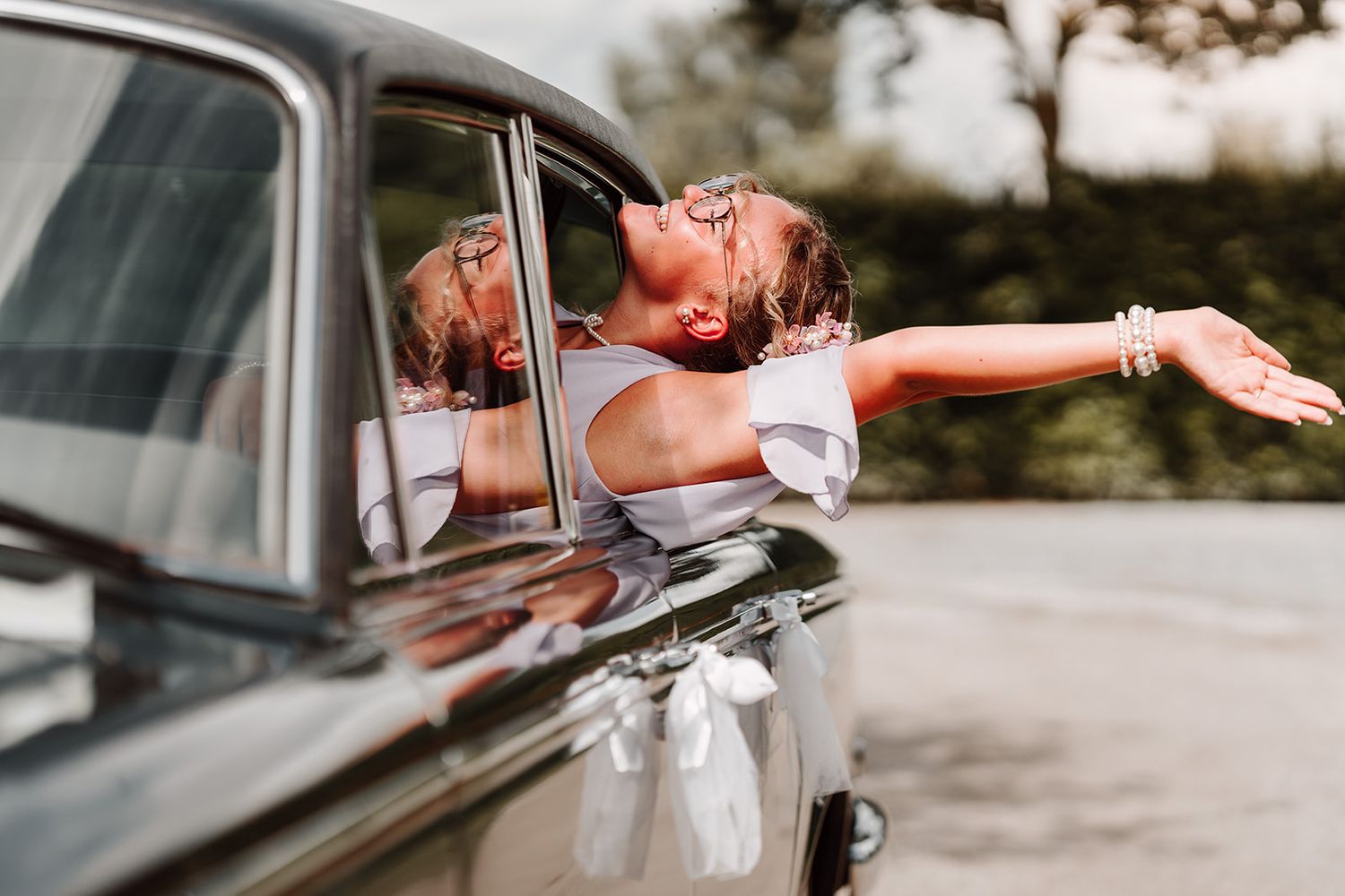 Joyful moment captured through vintage car window during wedding celebration.