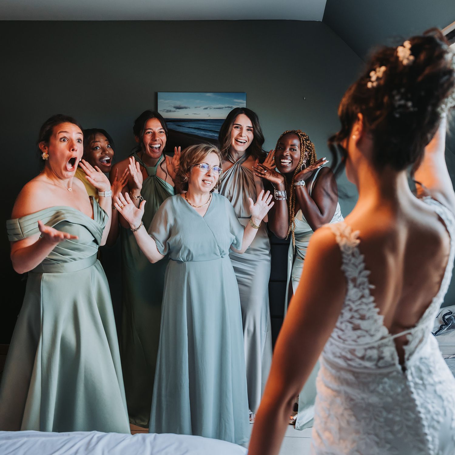 Bridesmaids in light blue dresses react with excitement upon seeing the bride.