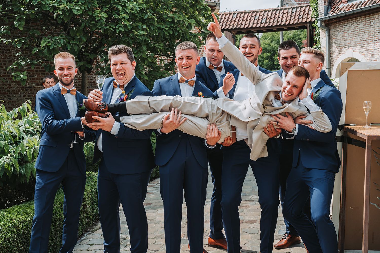 Groomsmen in navy suits strike playful poses in a series of candid wedding party photos.