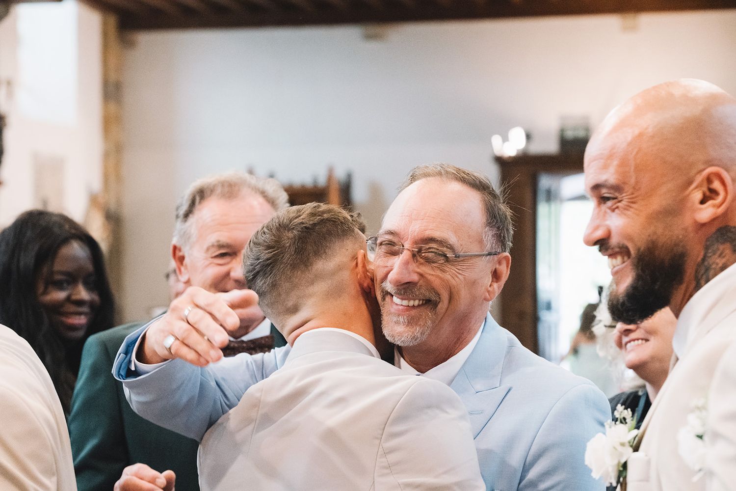 Wedding guests share warm embraces and smiles during reception celebrations.