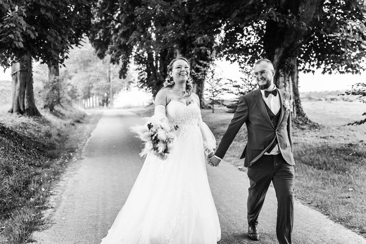 Wedding couple walks and poses along tree-lined paths in romantic outdoor settings.