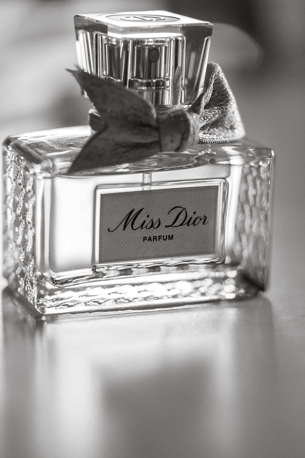 A black and white close-up of an elegant Miss Dior perfume bottle.