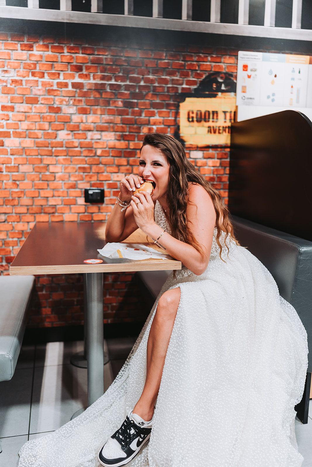 Bride in white dress sitting casually in sequence of playful poses against brick wall.