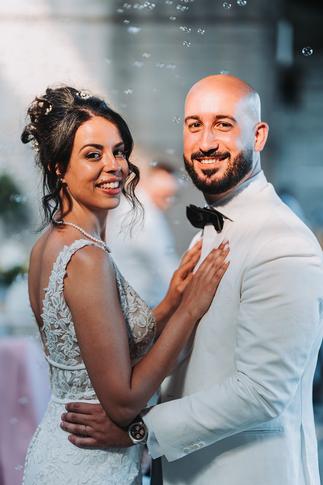 A joyful wedding couple sharing an intimate moment during their reception with bubbles floating in the background.