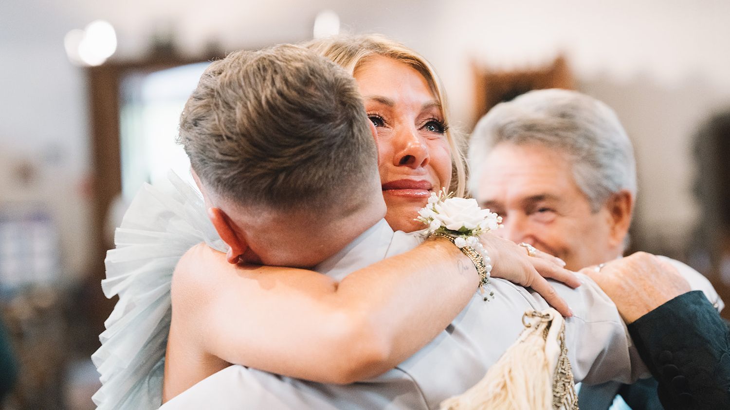Emotional embrace between wedding party members during reception celebration.
