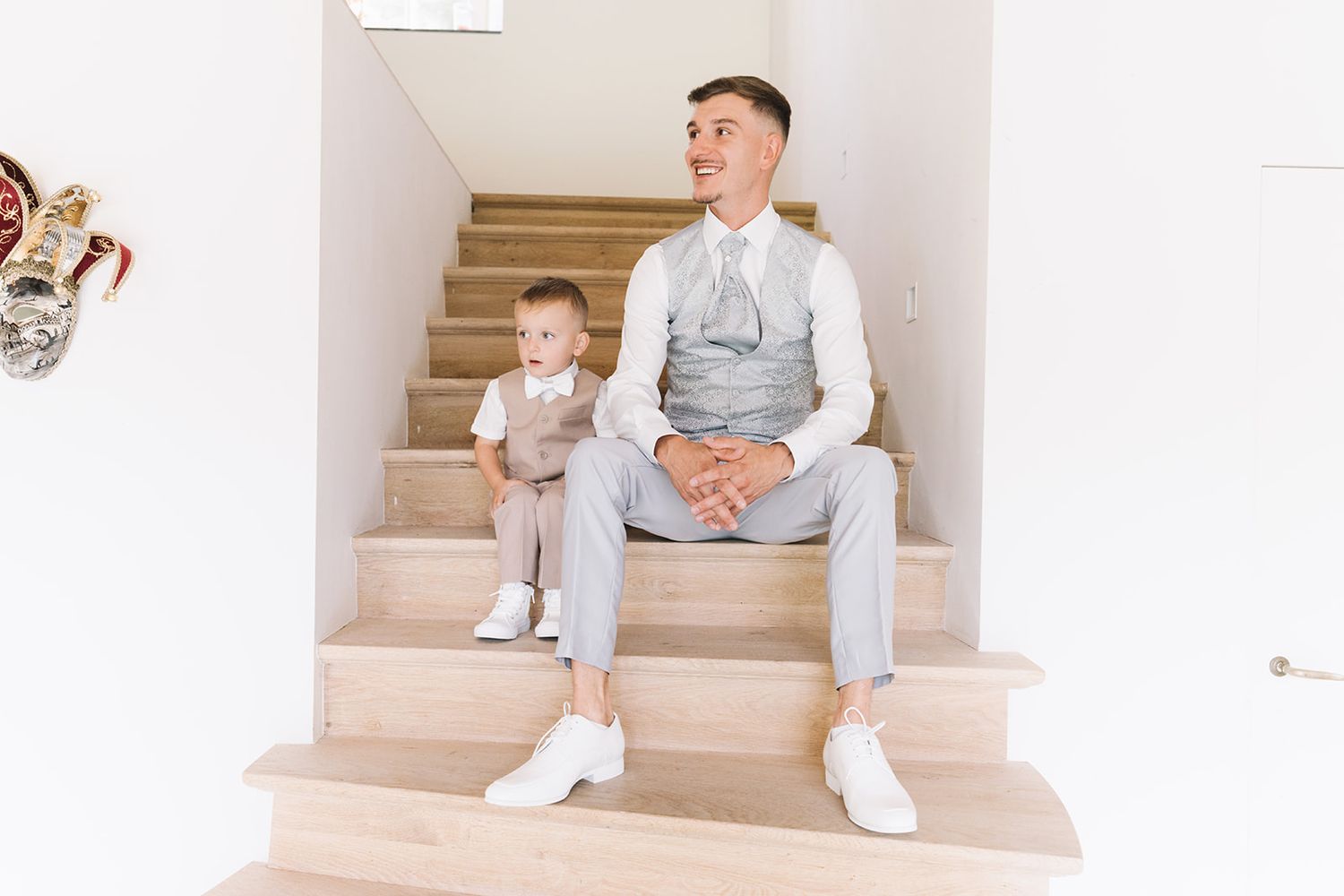 Wedding party members relaxing on light-colored stairs in formal attire.