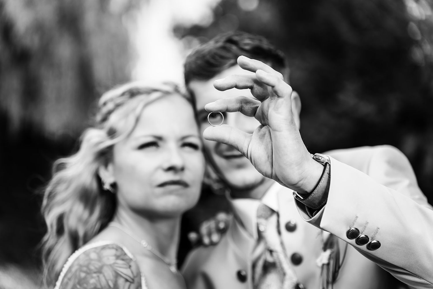 An artistic black and white portrait of a couple sharing a playful moment outdoors.