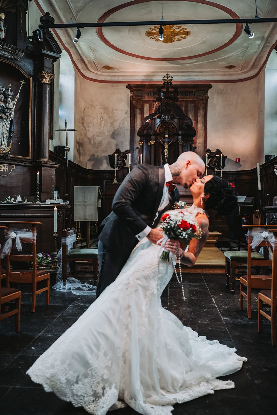 Romantic dip kiss in historic church with ornate architectural details.