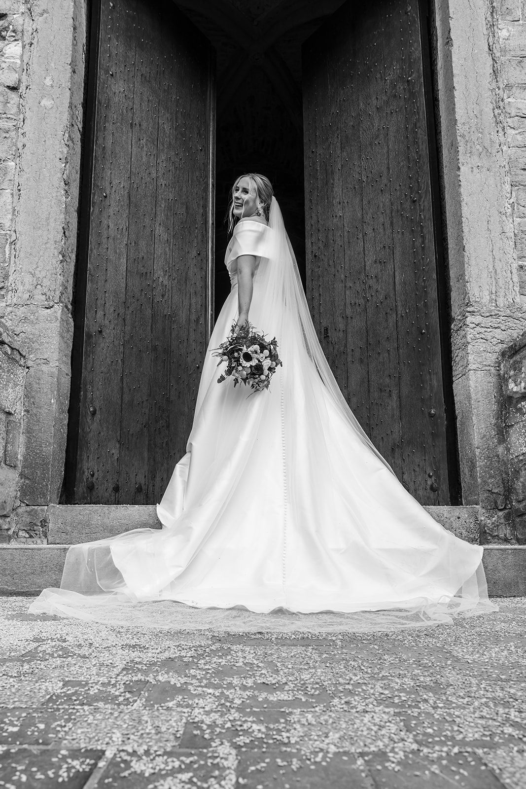Black and white series showing bride's dress train in dramatic architectural setting.