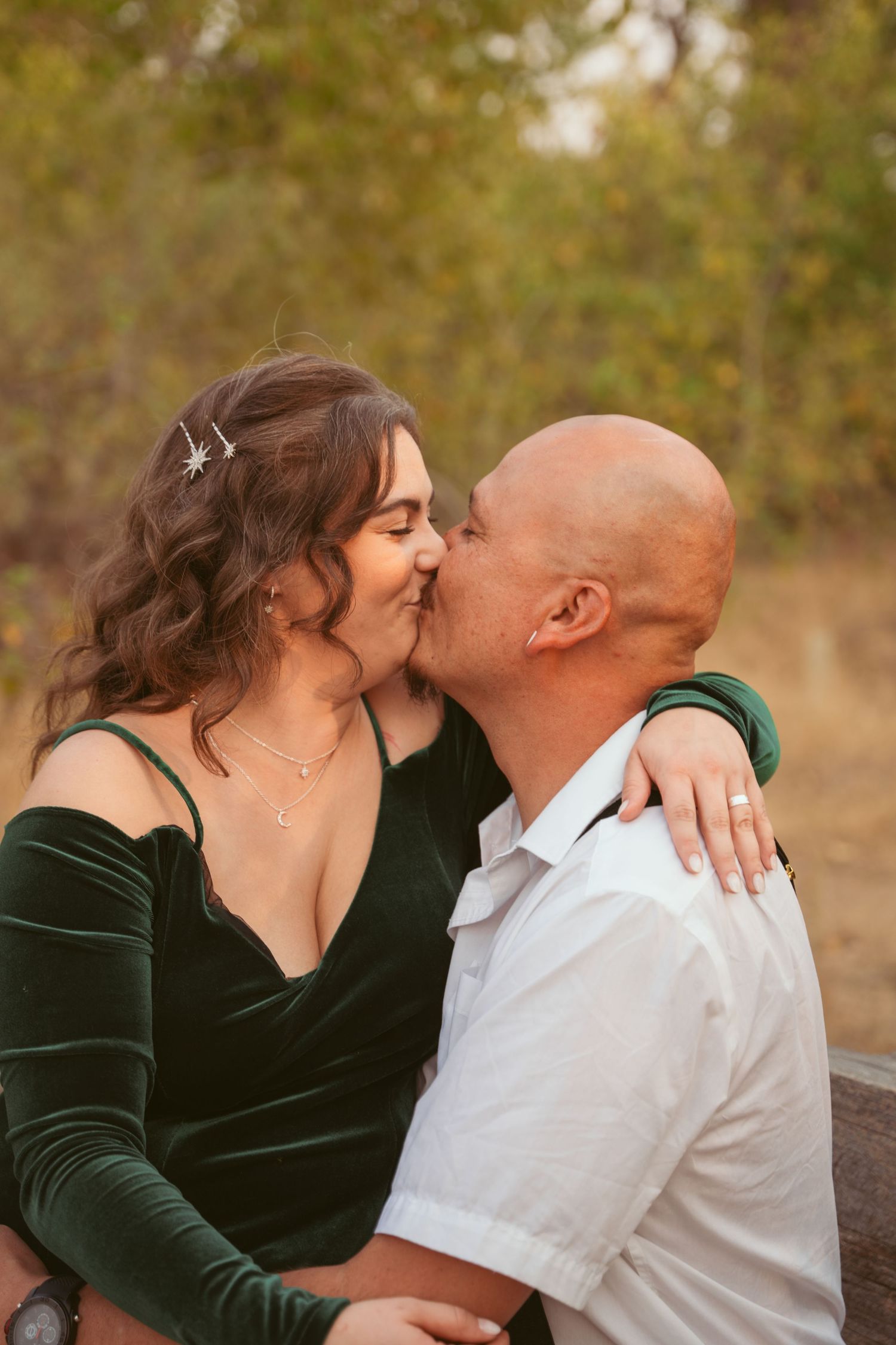 A romantic couple sharing an intimate kiss outdoors during an autumn photoshoot.