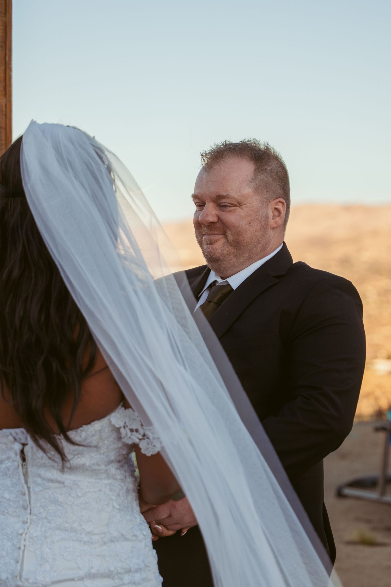 A tender wedding moment captured against a desert backdrop during golden hour.