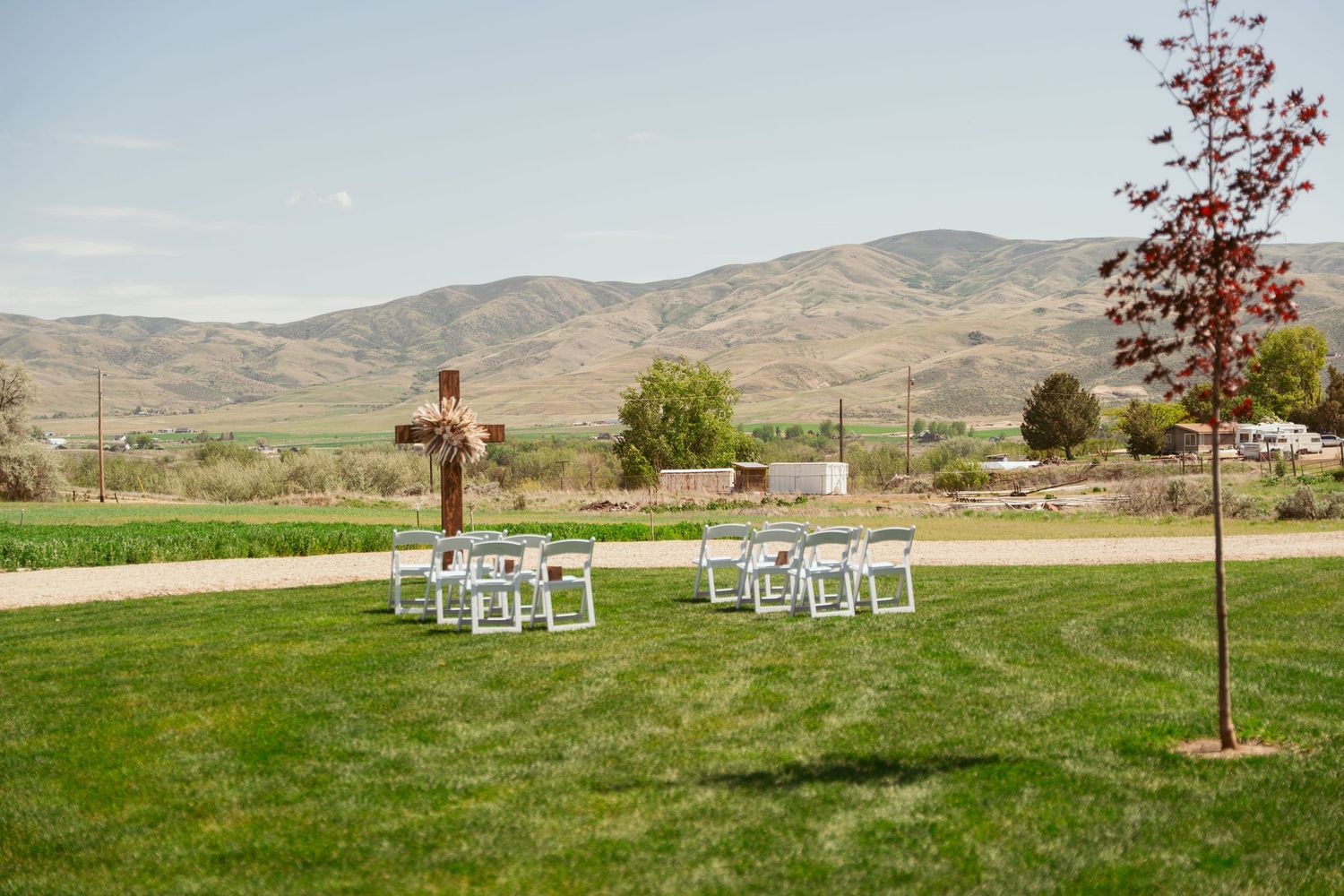 White chairs set up on a green lawn with mountains in the background for an outdoor event.