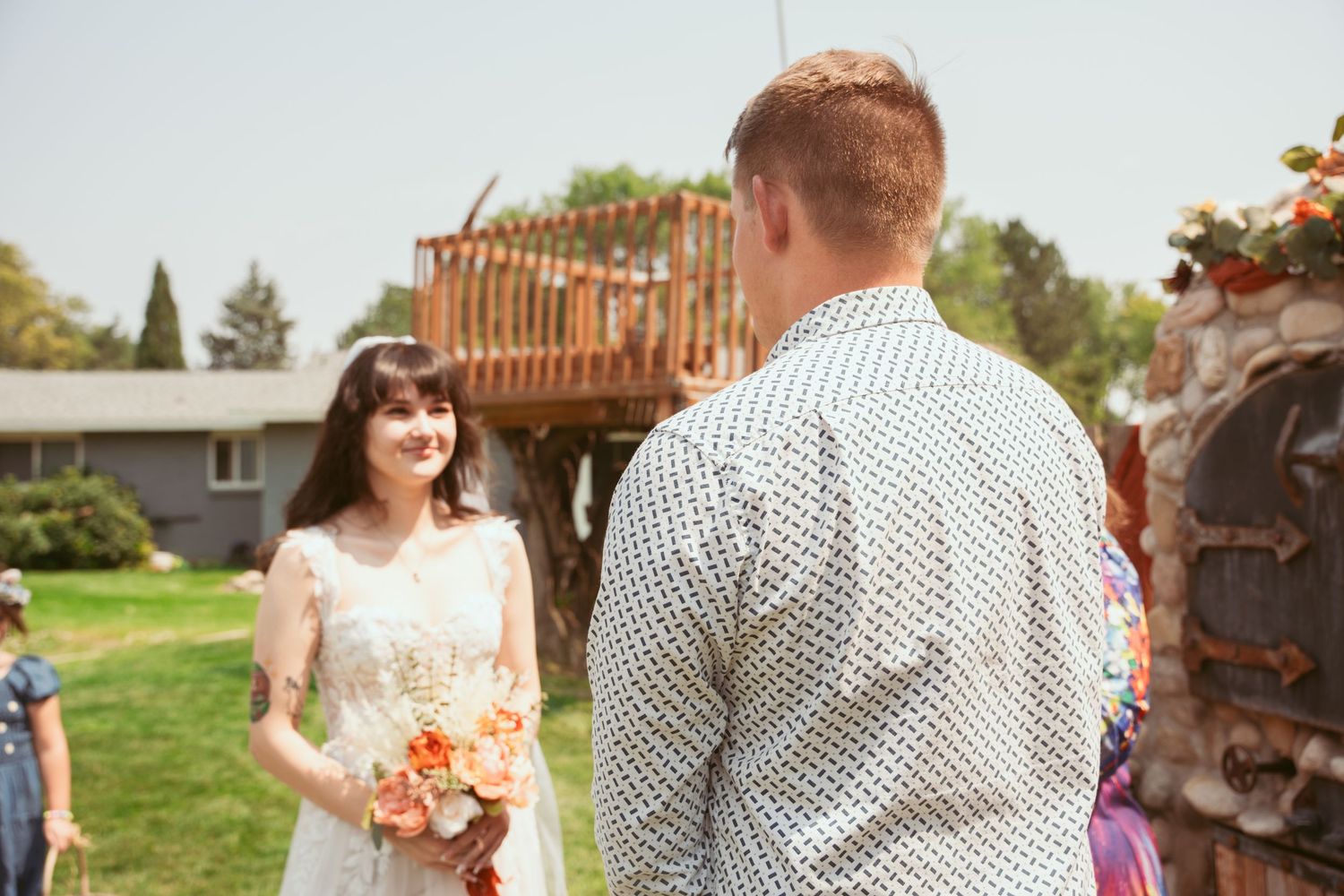 A couple shares a romantic moment during their outdoor wedding ceremony with floral decorations.