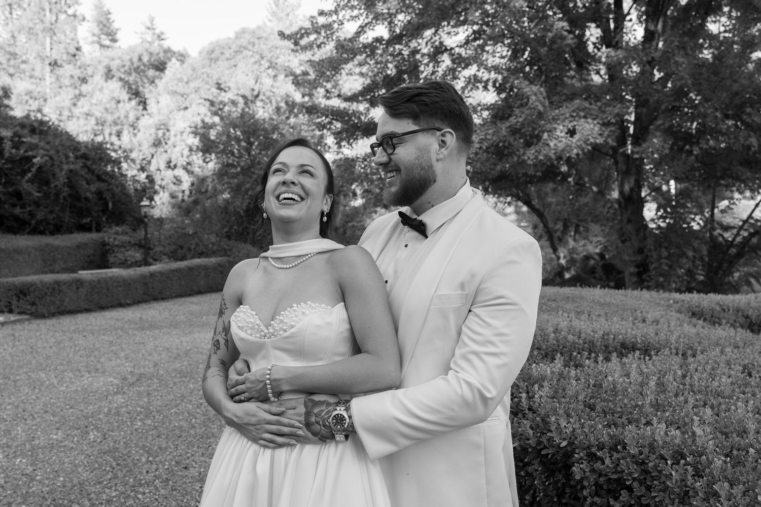 A candid black and white photo of a joyful couple embracing and laughing together outdoors.