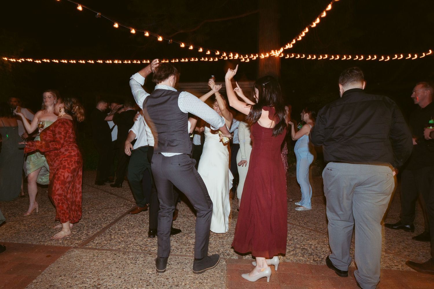 Wedding party members dancing and jumping energetically during the reception celebration.