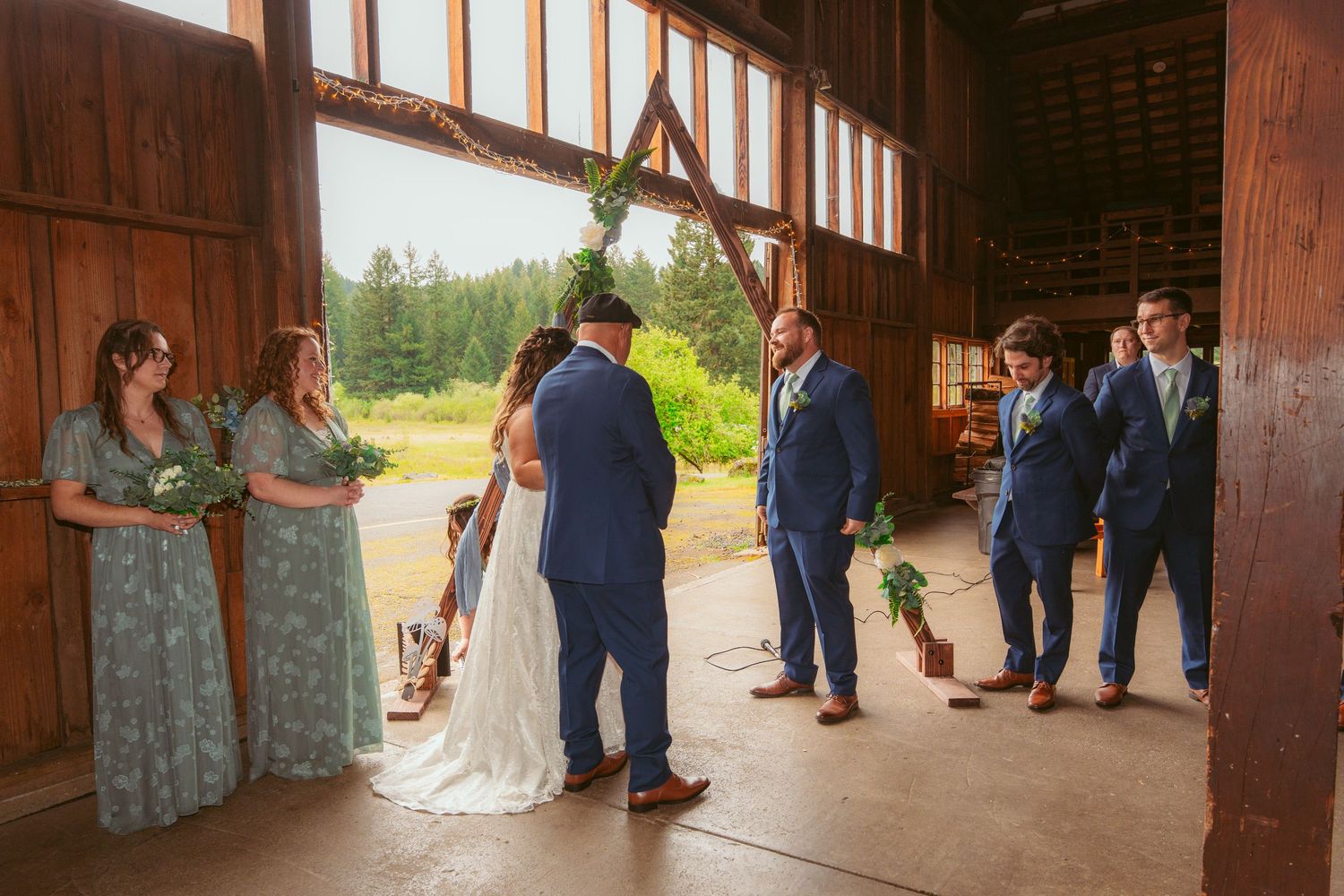 Panoramic view of wedding ceremony setup inside spacious wooden barn with natural lighting.
