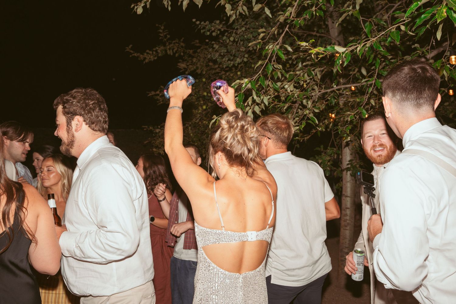 Wedding party guests dancing in formation during an outdoor nighttime celebration.