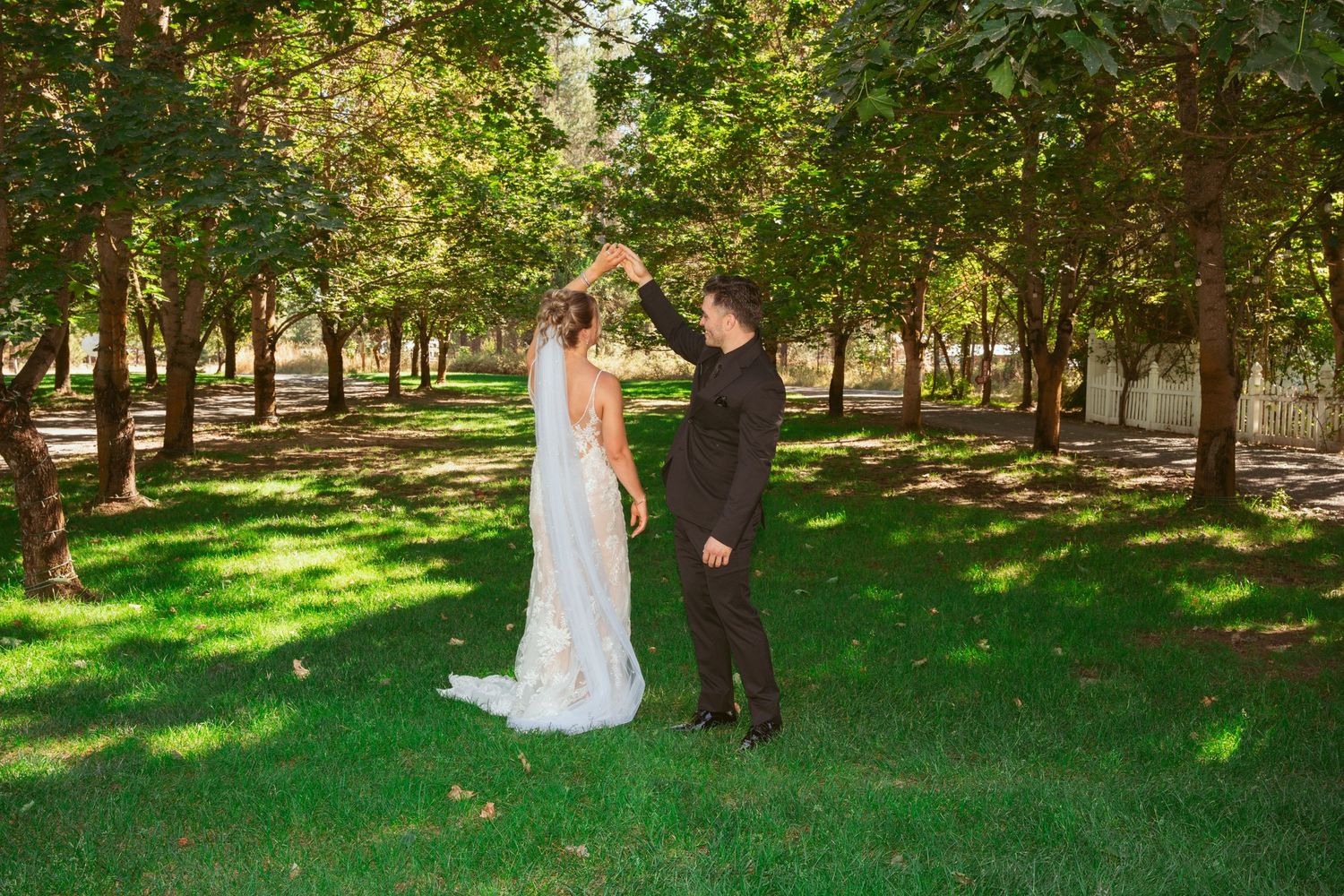 Wedding couple standing together in a serene tree-lined park.
