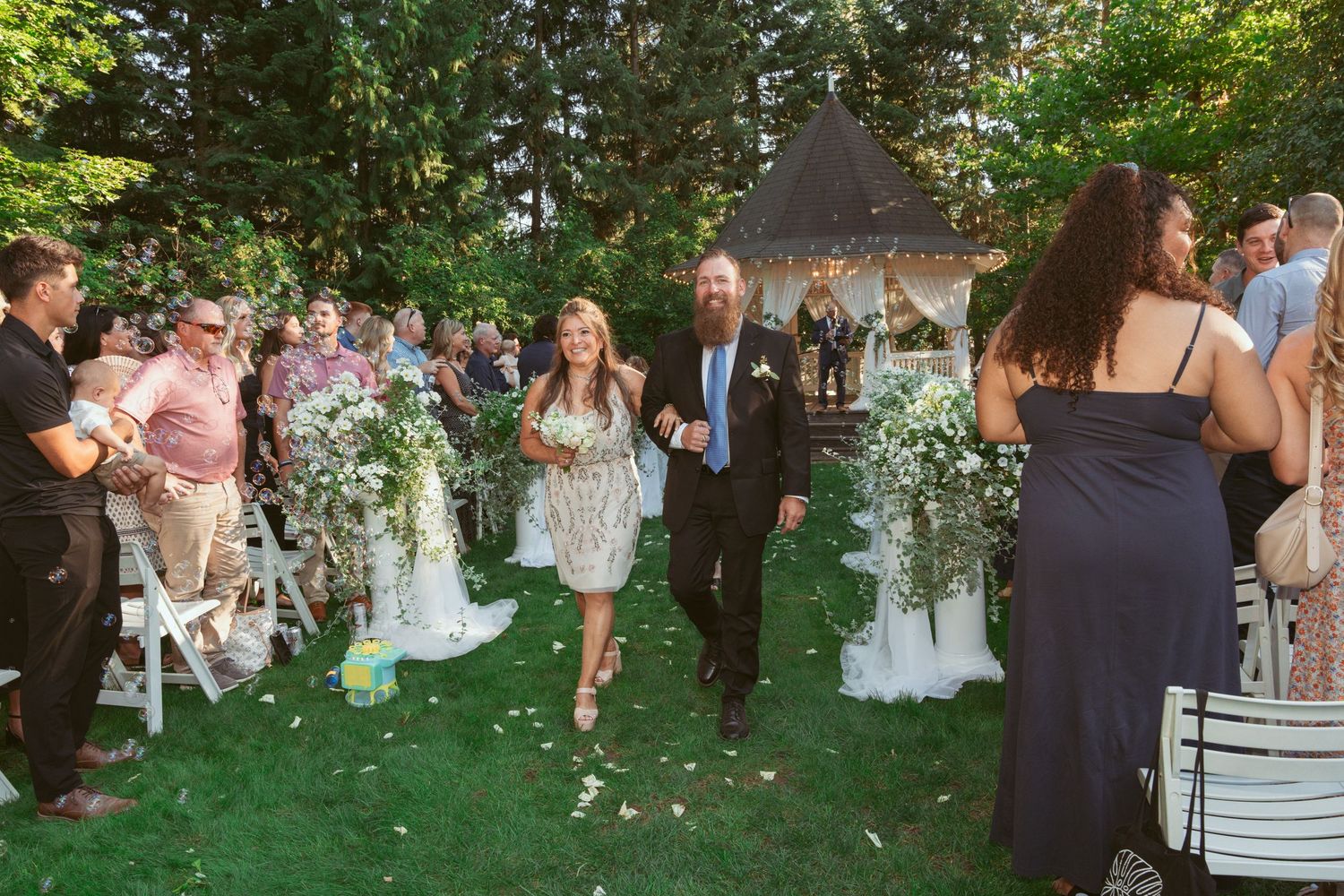Guests mingle on a beautifully landscaped lawn during an outdoor wedding reception.