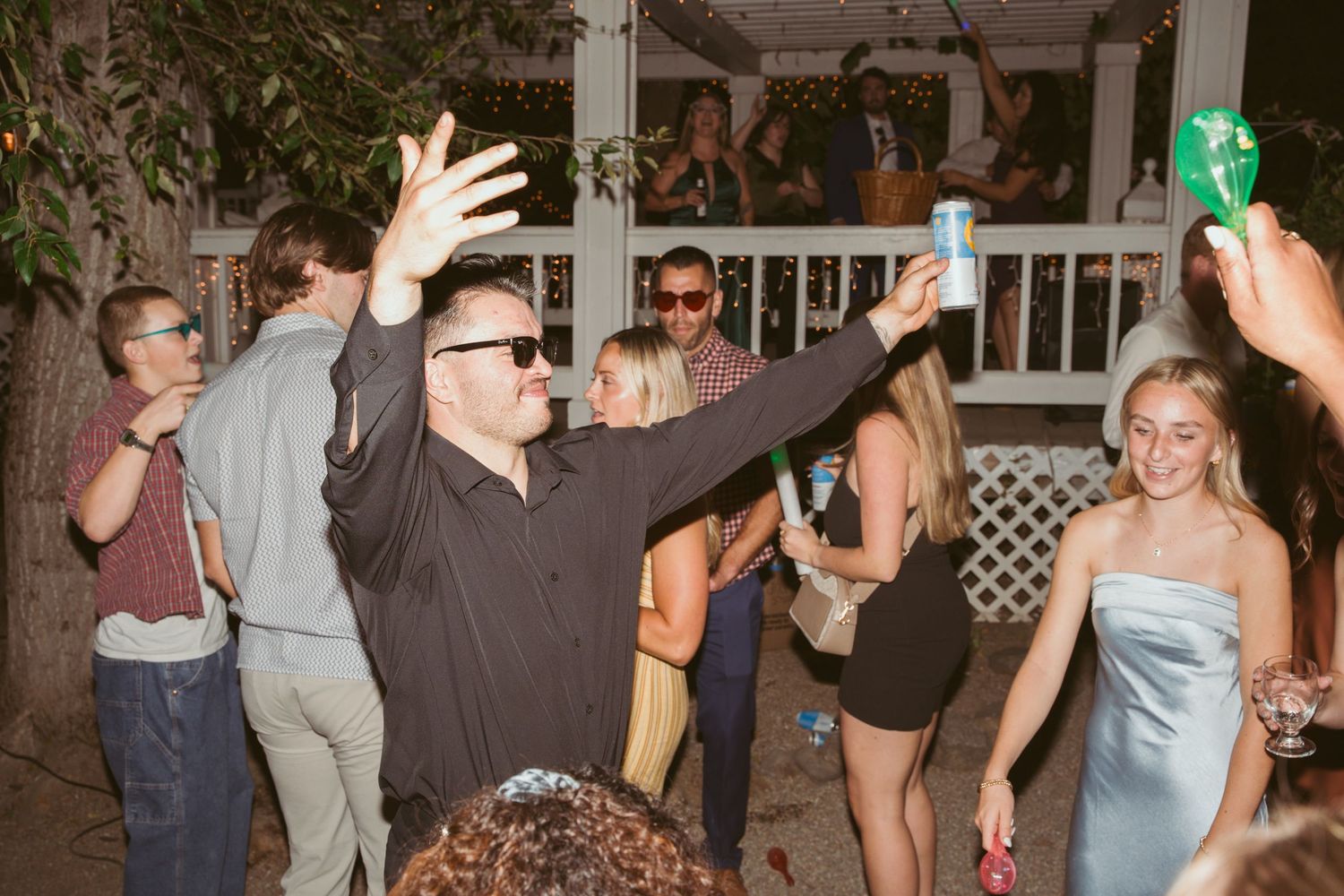 Crowd of people dancing with raised hands at an outdoor party venue.