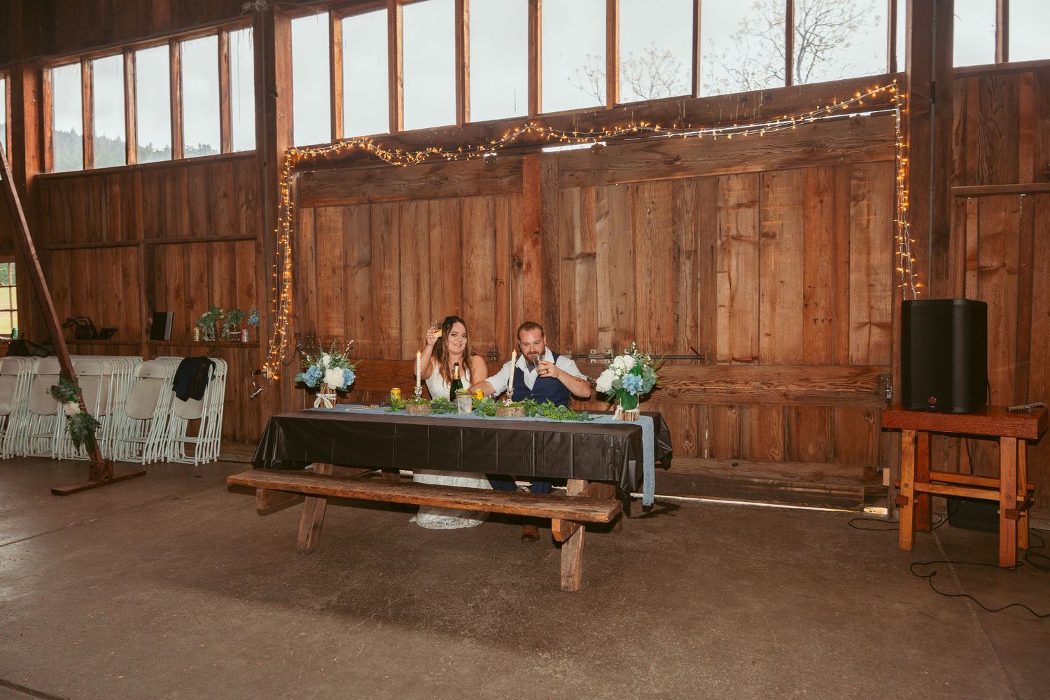 Wide angle view of a barn reception space with wooden beams and natural lighting.