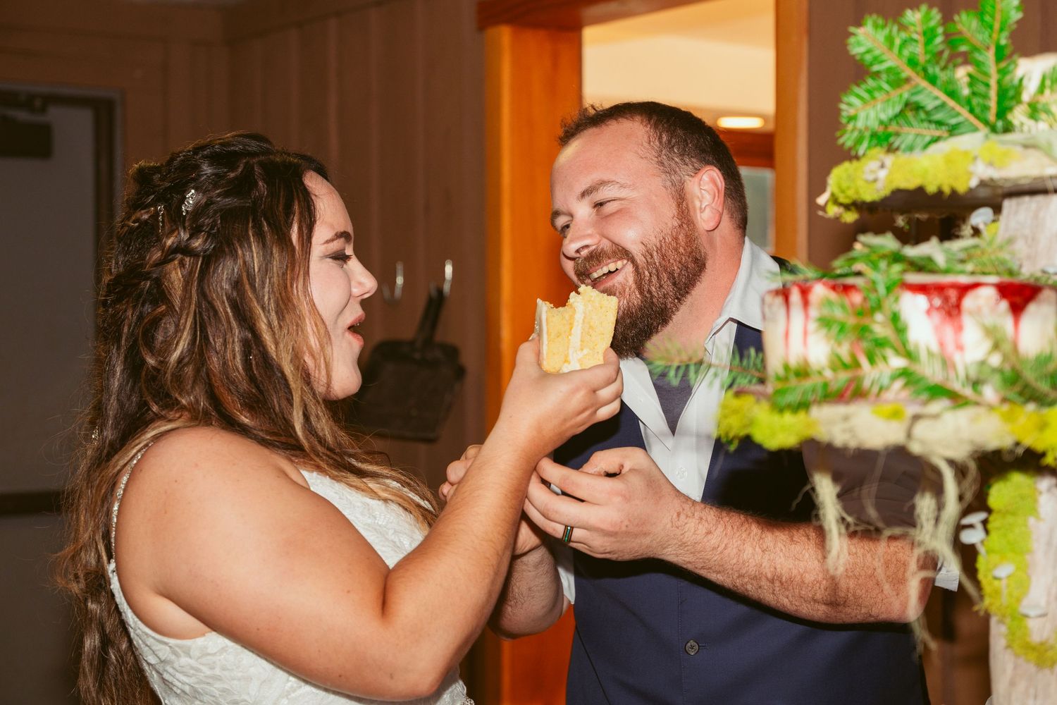Bride and groom share a joyful moment during their wedding cake tasting tradition.