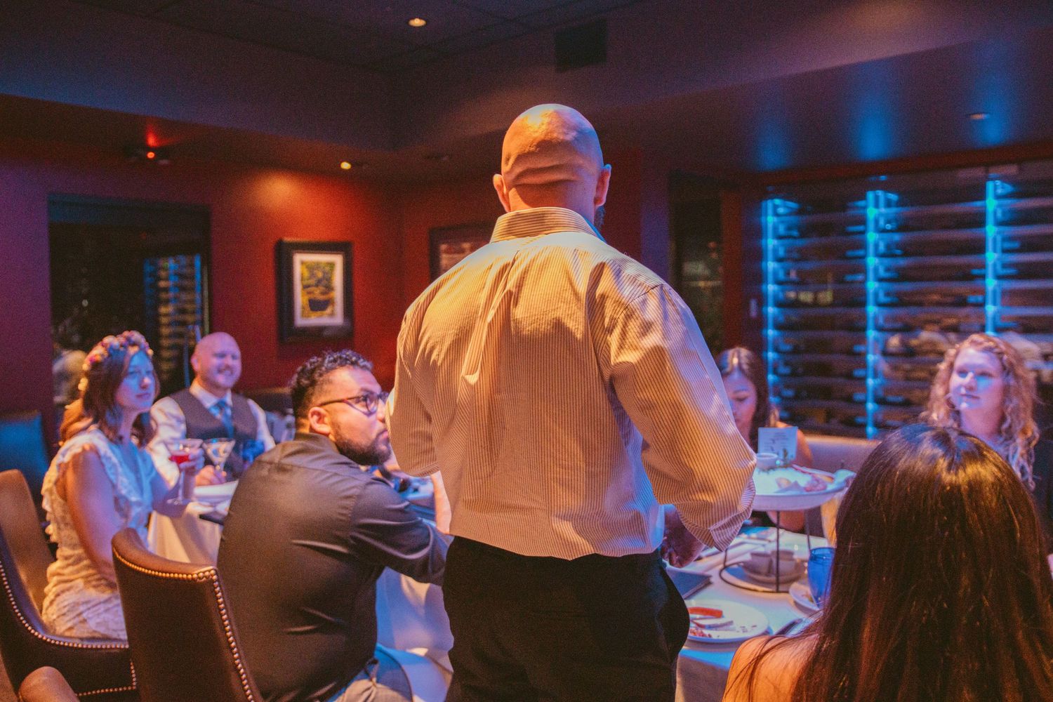 Reception venue with warm ambient lighting and guests gathered at tables.