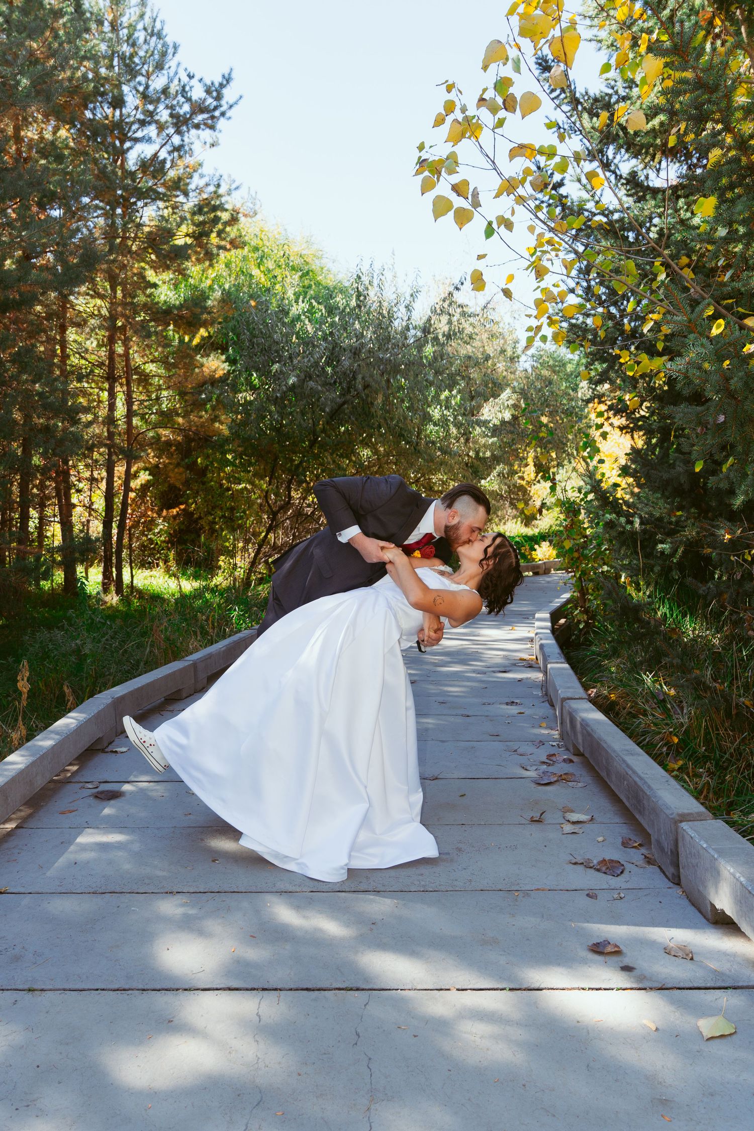 Couple sharing a romantic dip pose on a garden pathway surrounded by autumn foliage.