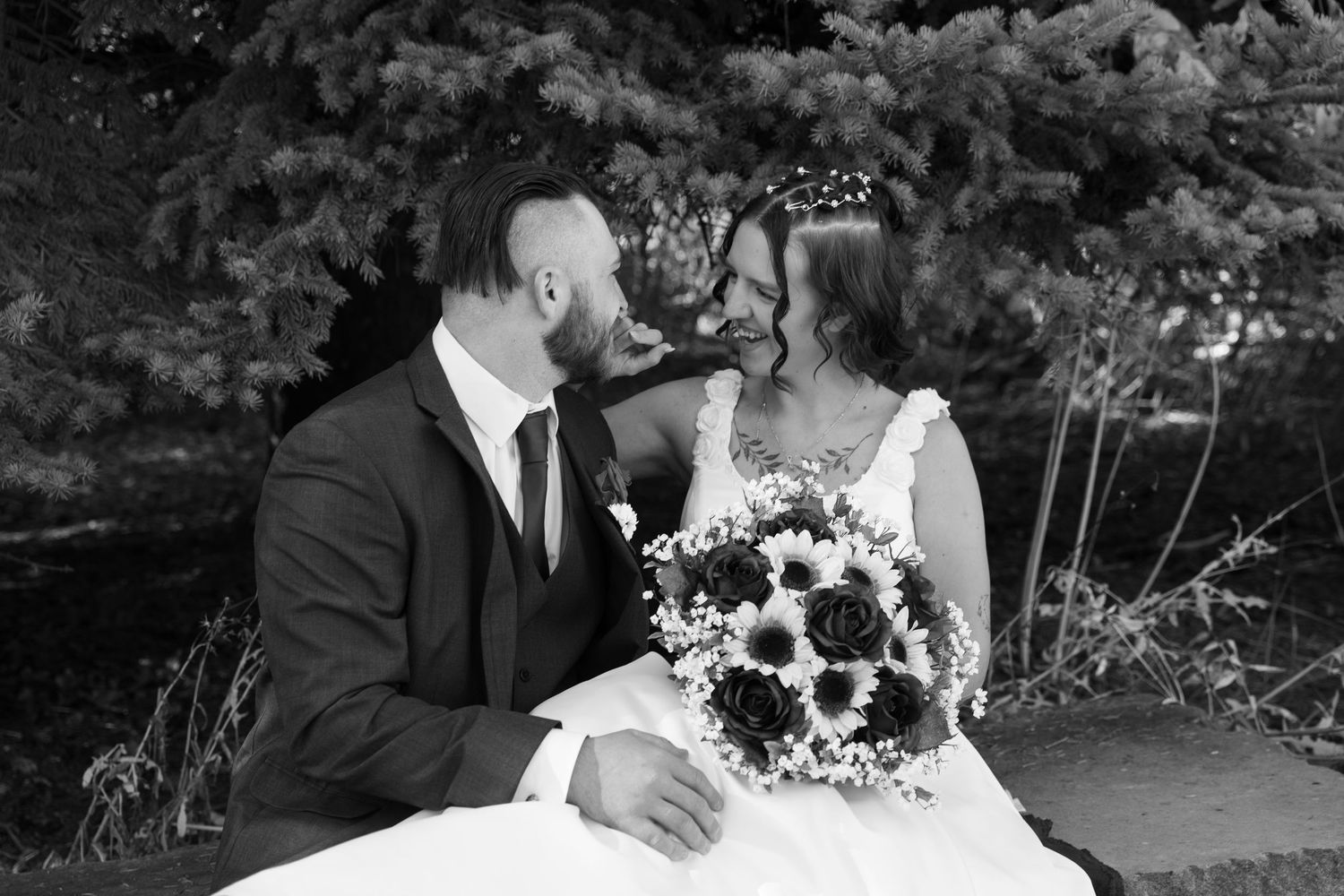 Black and white portrait of a wedding couple sharing an intimate moment with sunflower bouquet.