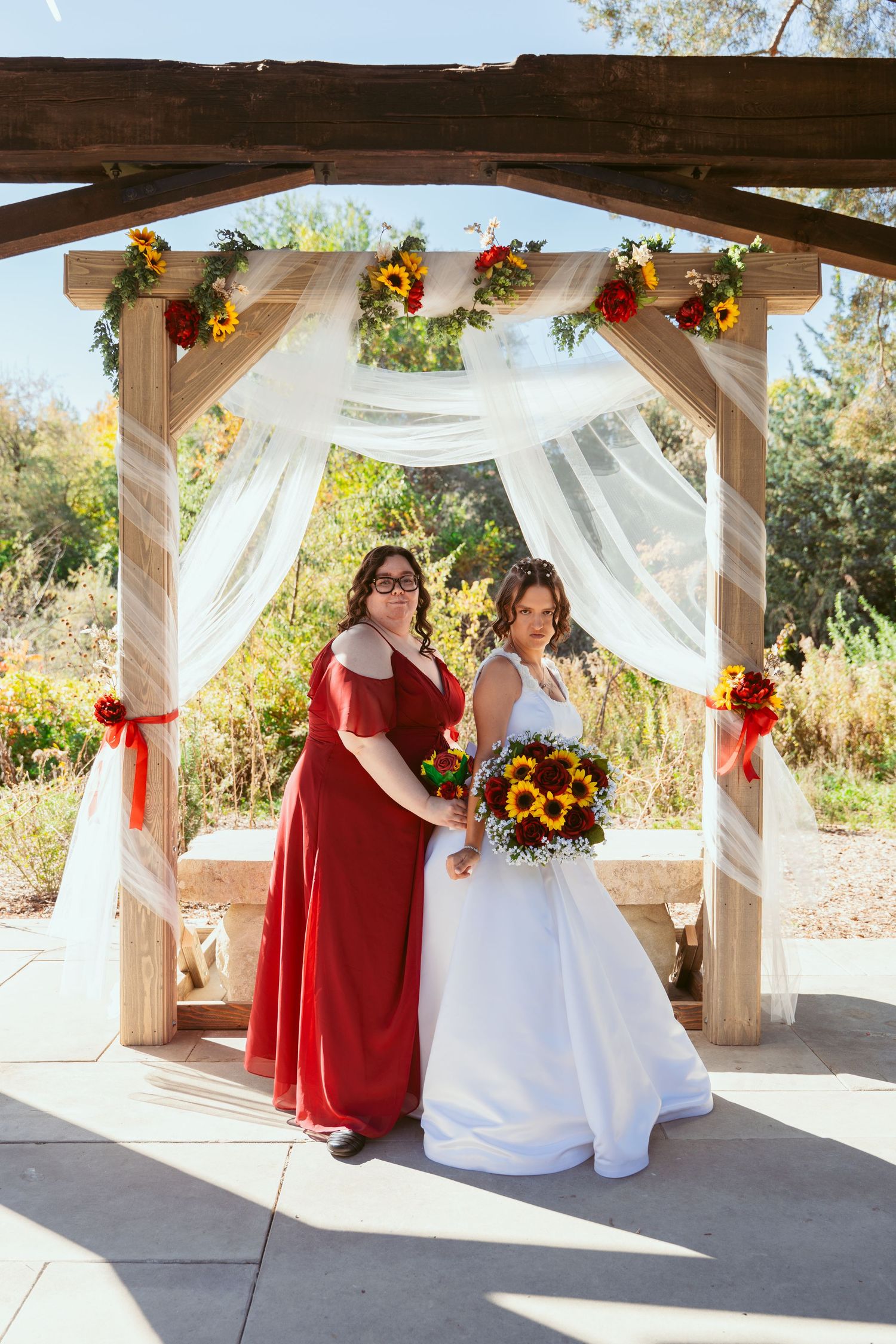 Wedding celebration under decorated pergola with white draping and sunflower accents.