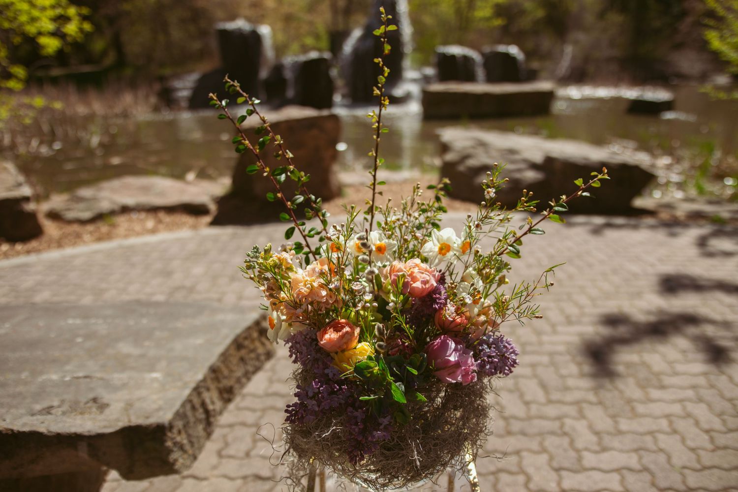 A rustic floral arrangement with wildflowers and roses in a glass vase.