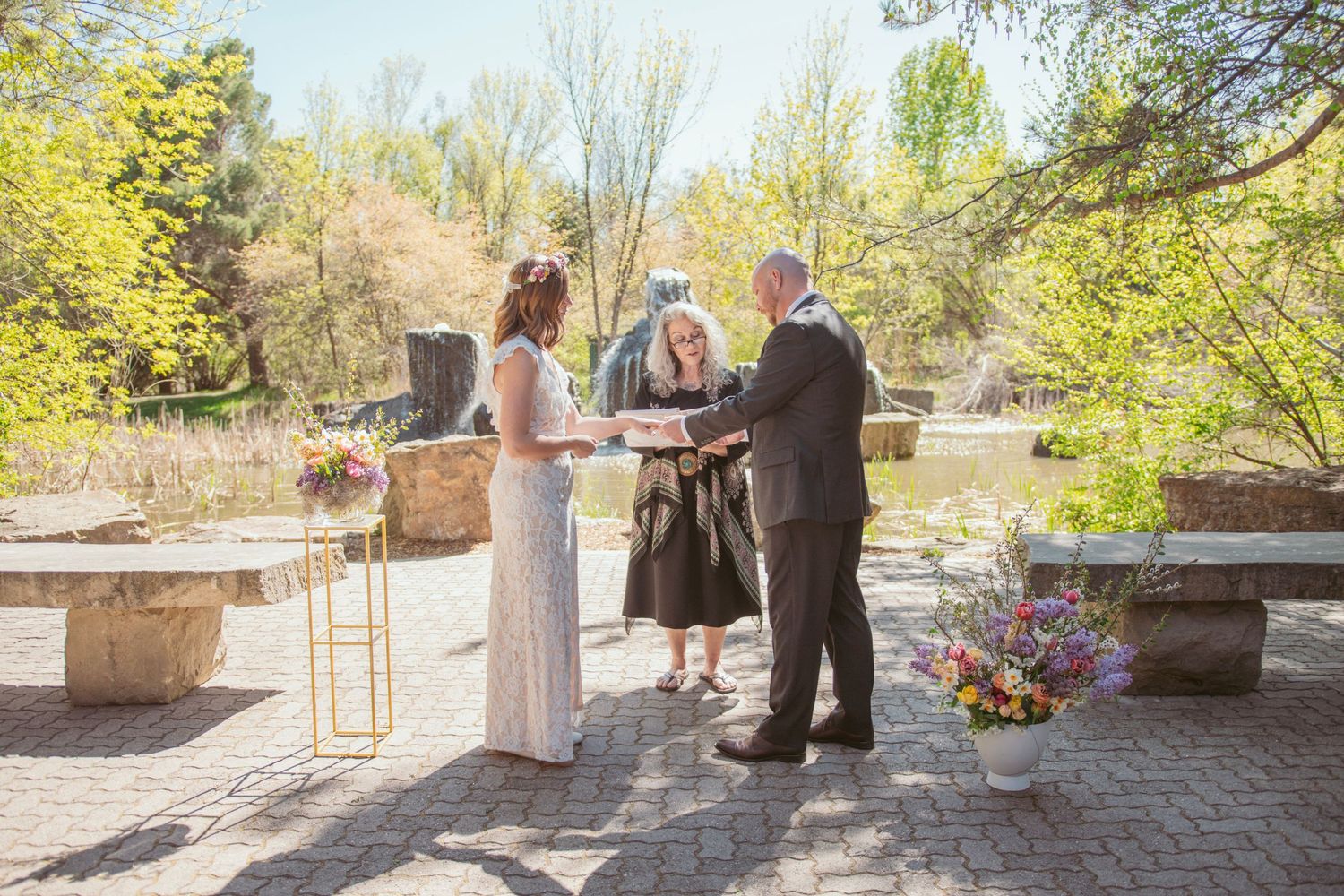 Wedding ceremony setup on a stone patio with natural lighting and spring foliage.