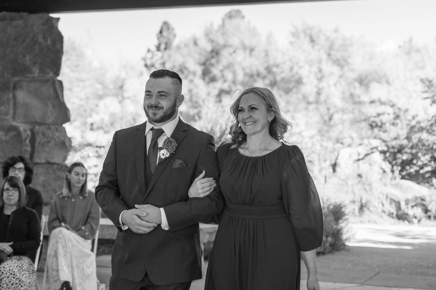Black and white wedding ceremony photos showing tender moments under outdoor pavilion.