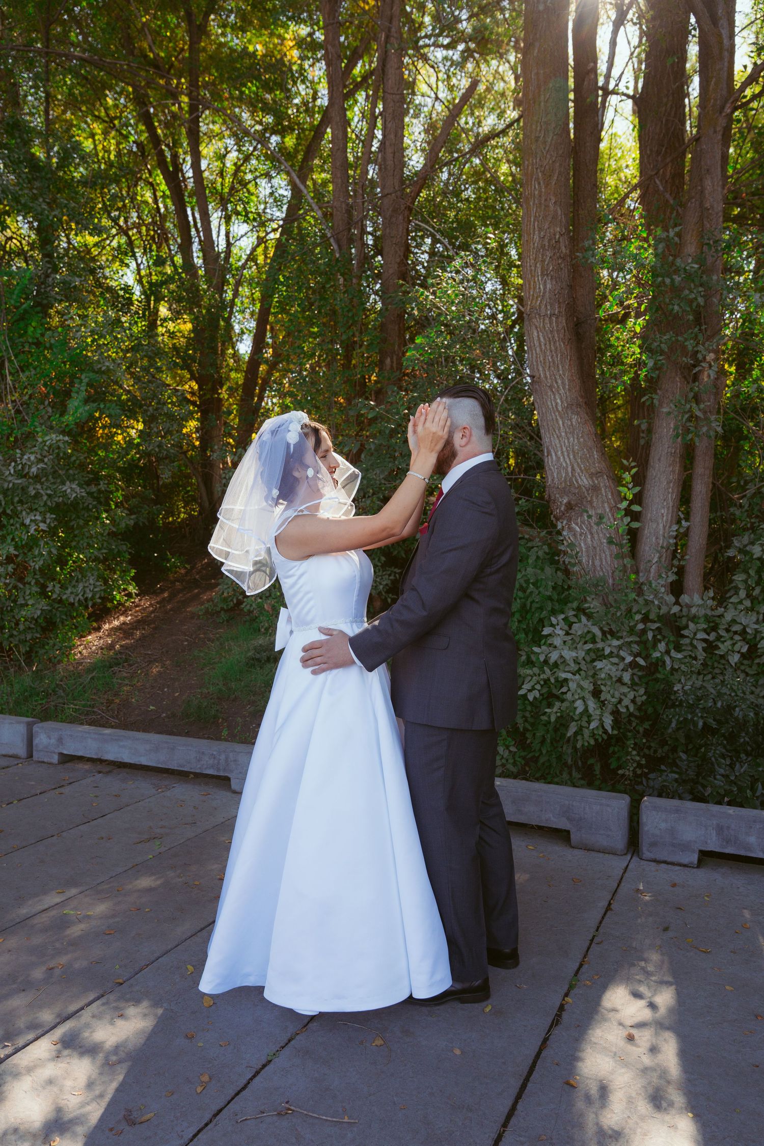 Wedding couple dancing on wooden deck surrounded by lush greenery.