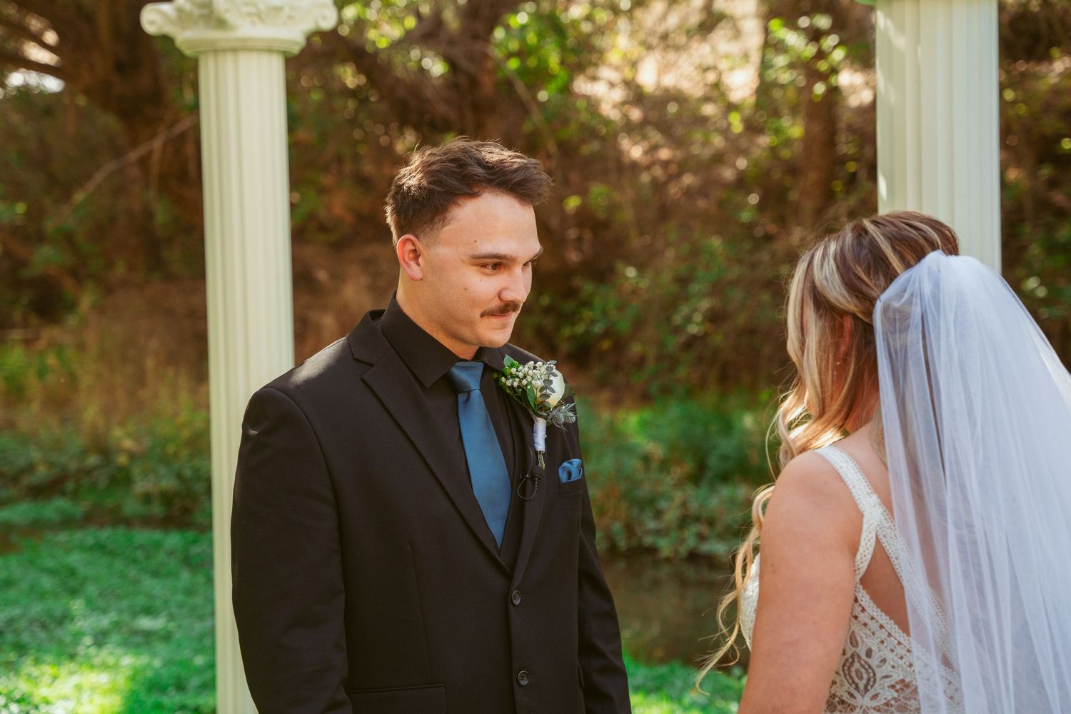 Couple reading personal vows to each other during outdoor garden wedding ceremony.